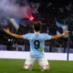 Un giocatore con la maglia biancoceleste esulta sotto la curva dopo un gol